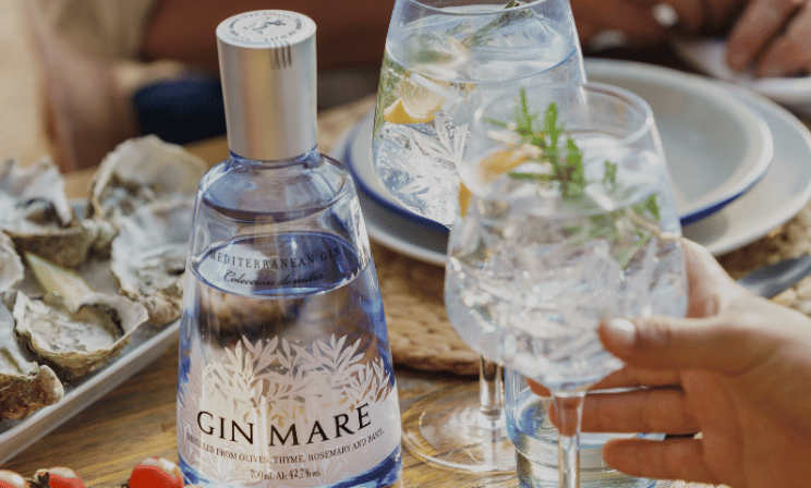 Eine Hand hält ein dekoriertes Glas Gin Mare